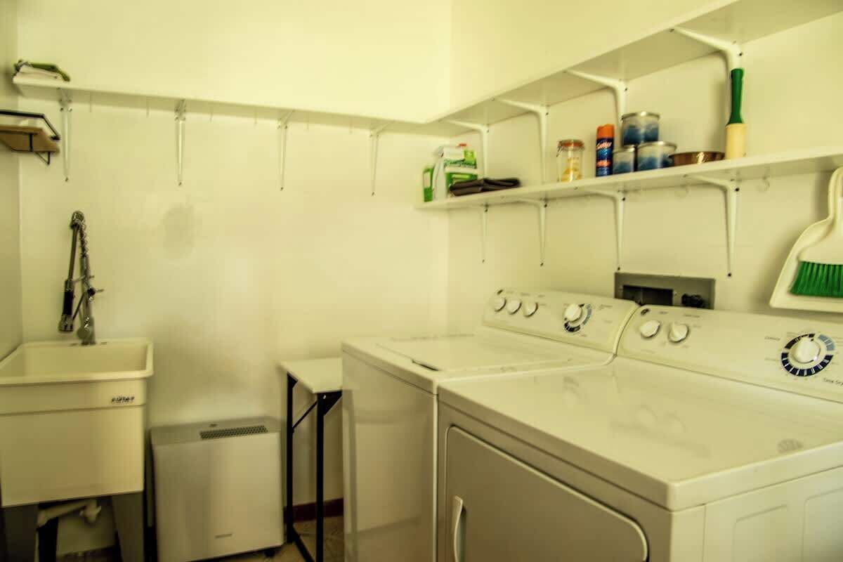 A laundry area with a washing machine, a dryer, and shelves with cleaning supplies.