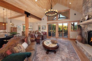 A spacious living room with a fireplace, leather sofas, a dining area, and a large window overlooking a deck. - Luxury Mountain Home with Private Hot Tub and Stunning Mountain Views (Silverthorne)