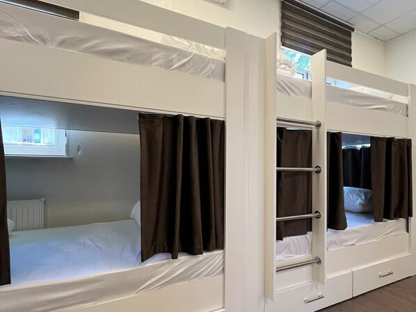 Bunk beds with curtains, a window, and a radiator.