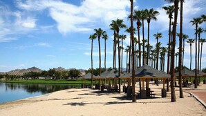 Zona de playa con palmeras, un lago y un campo de golf al fondo.