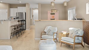 Una cocina moderna con gabinetes blancos, electrodomésticos de acero inoxidable y una zona de bar con taburetes.