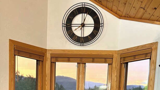 A corner room with large windows, two leather chairs, a wooden table, and a wall-mounted clock. - Spacious retreat with Stunning views of Mount Washington!! 3Bedroom + 2Bath (Bartlett)