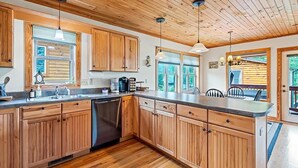 A spacious kitchen with wooden cabinets, a dishwasher, and a large island with a sink. - Watch the Elk from the Deck! Hot Tub, High Speed Wifi, Paved Access (Maggie Valley)