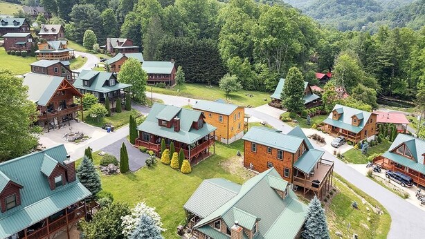 A lodge with multiple buildings, each featuring a green roof and surrounded by lush greenery and mountains. - Watch the Elk from the Deck! Hot Tub, High Speed Wifi, Paved Access (Maggie Valley)