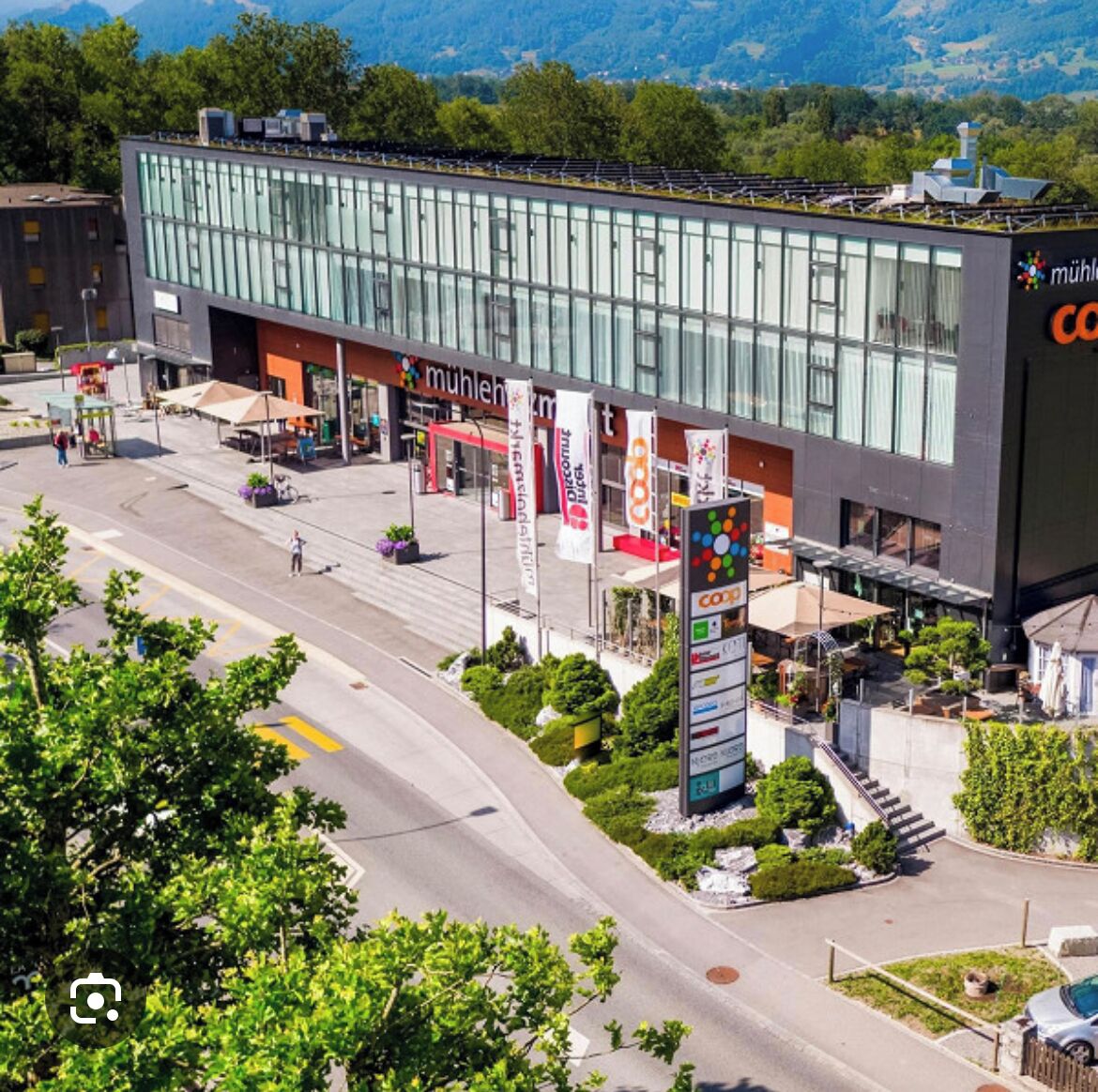 A modern building with large glass windows, a rooftop garden, and a sign for 'muhlenberg'.