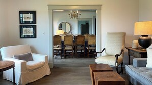 Una sala de estar con sofá, sillones, una mesa de centro y un comedor con candelabro.