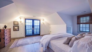 Un dormitorio con una cama grande, un aparador de madera, una puerta con vistas y una ventana con persianas.