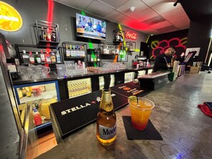 A bar area with a television, various bottles, and a bottle of Modena wine.