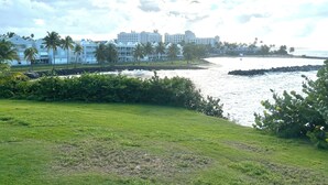 A coastal hotel with a view of the ocean, palm trees, and a grassy area. - Golf & Casino Beach Villa @Dorado del Mar (Dorado)