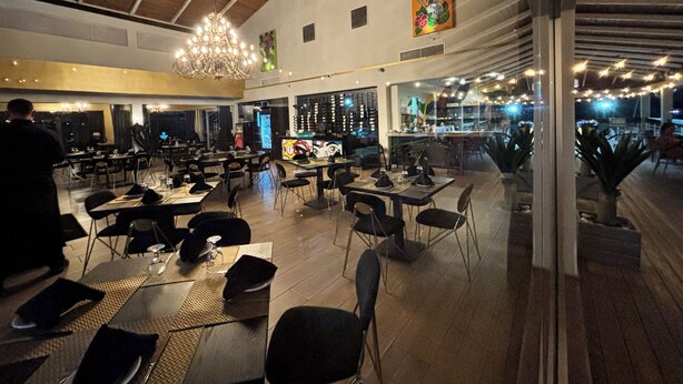 A restaurant with high ceilings, chandeliers, and a bar area. Tables are set with chairs, and there are large windows. - Golf & Casino Beach Villa @Dorado del Mar (Dorado)