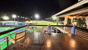 A nighttime view from a balcony overlooking a sports field with seating and a covered area. - Golf & Casino Beach Villa @Dorado del Mar (Dorado)