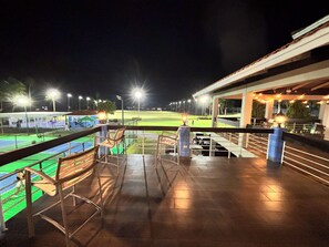 Una vista notturna da un balcone su un campo sportivo con posti a sedere e una zona coperta.