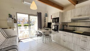 A modern kitchen with a dining area, a sofa, and a view of the outdoors. - Air-conditioned holiday home for 5 people, secure residence MAS DE LA PLAGE, south-facing... (PORTIRAGNES)