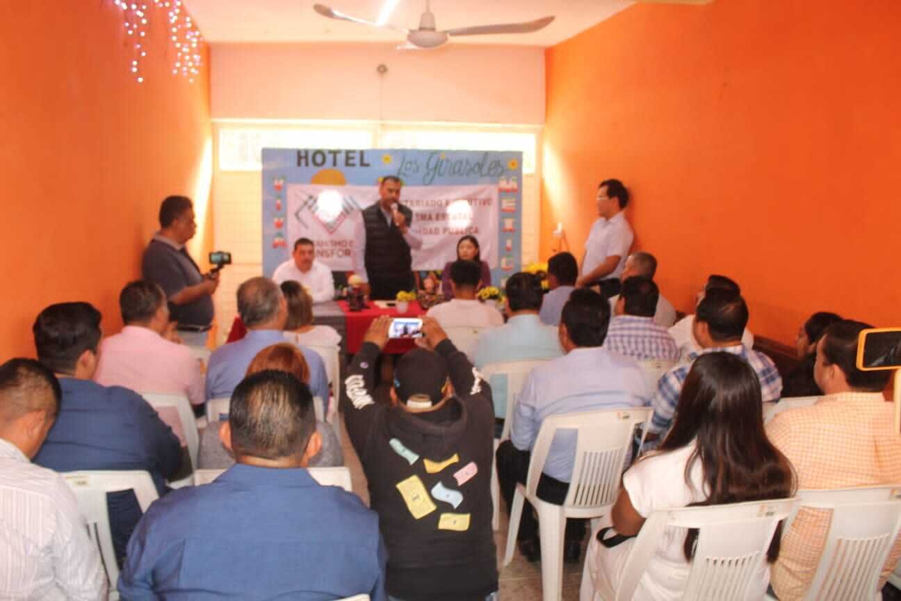 A conference room with attendees seated facing a stage where a speaker is presenting.