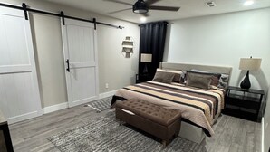 Une chambre à coucher avec un lit, des tables de chevet, un ventilateur de plafond et un tapis.