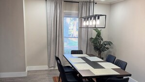 Une salle de conférence avec une longue table, des chaises noires, un tapis à rayures, un luminaire suspendu et une plante en pot.