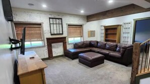 A spacious room with a large leather sofa, a wooden desk, and a bookshelf.