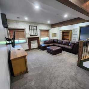A spacious room with a large leather sofa, a wooden desk, and a bookshelf.
