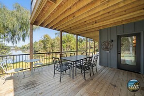 Een houten terras met een tafel en stoelen, met uitzicht op een meer.