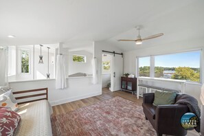 Ruime kamer met een bed, een zithoek, uitzicht op een rivier en een groot raam.