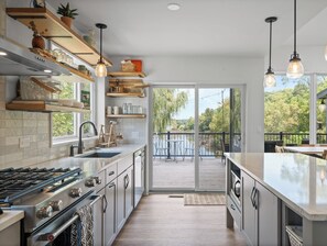 A modern kitchen with a large island, built-in appliances, and a view to a deck. - Modern Whitewater Lake Retreat on Private Cove with Views Screened Porch (Whitewater)