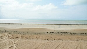 A beach with a clear sky and calm sea. - Apto Pet Friendly com Piscina a 100m da Orla (Japaratinga)