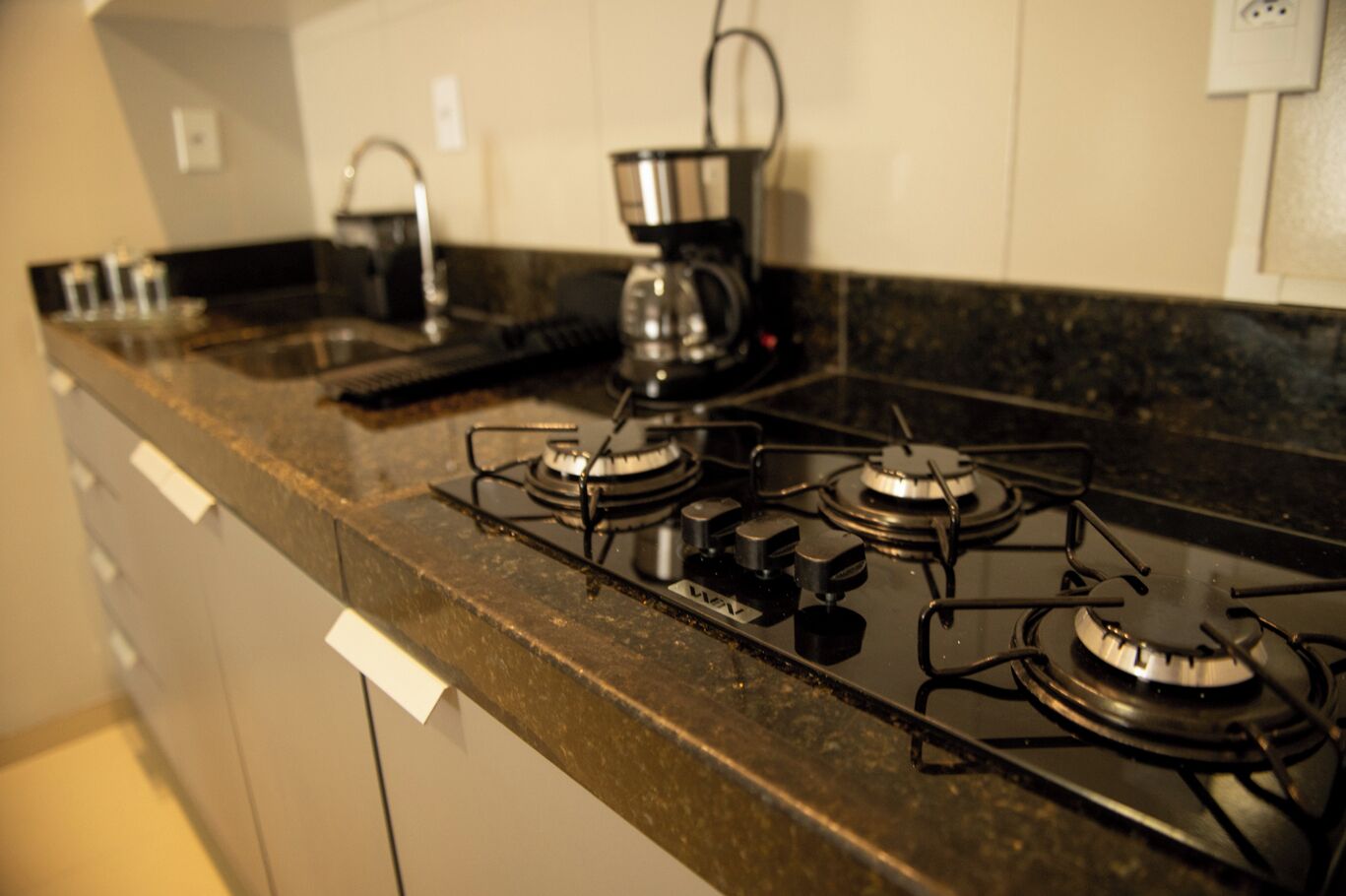 A kitchen with a gas stove, a coffee maker, and a sink.