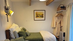Une chambre confortable avec un lit, un canapé, une lampe suspendue, un radiateur et une fenêtre avec des rideaux.