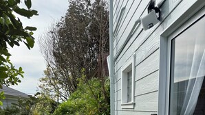 Une terrasse avec un banc, une porte vitrée et un mur extérieur blanc.
