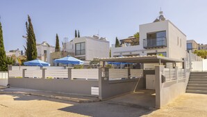 A gated parking area with a modern building in the background. - Lenia's Sea view, pool, gazebo and breathtaking views (Latchi)