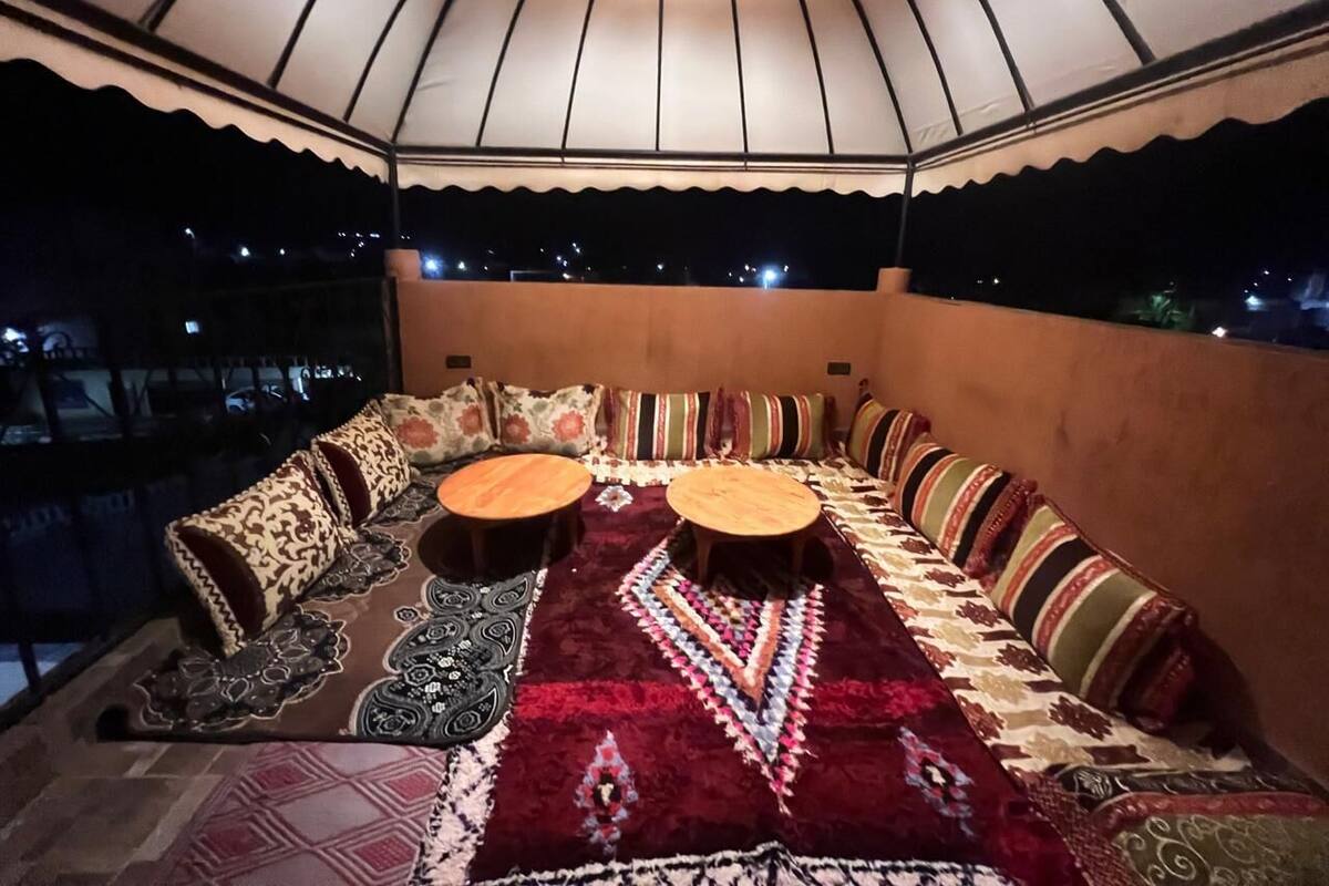 A cozy, well-lit seating area with a patterned rug, cushioned sofas, and wooden tables, featuring a large, curved ceiling structure.