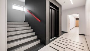 Eine moderne Treppe mit roter Handlauf, die zu einer dunklen Wand und einer Tür führt.