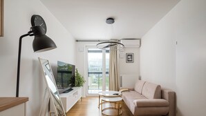 Ein modernes Wohnzimmer mit Sofa, Couchtisch, Fernseher und Lampe.