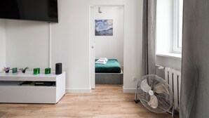 A modern bedroom with a bed, a TV, a fan, and a painting on the wall. - Marszałkowska City Centre Apartment (Warszawa)