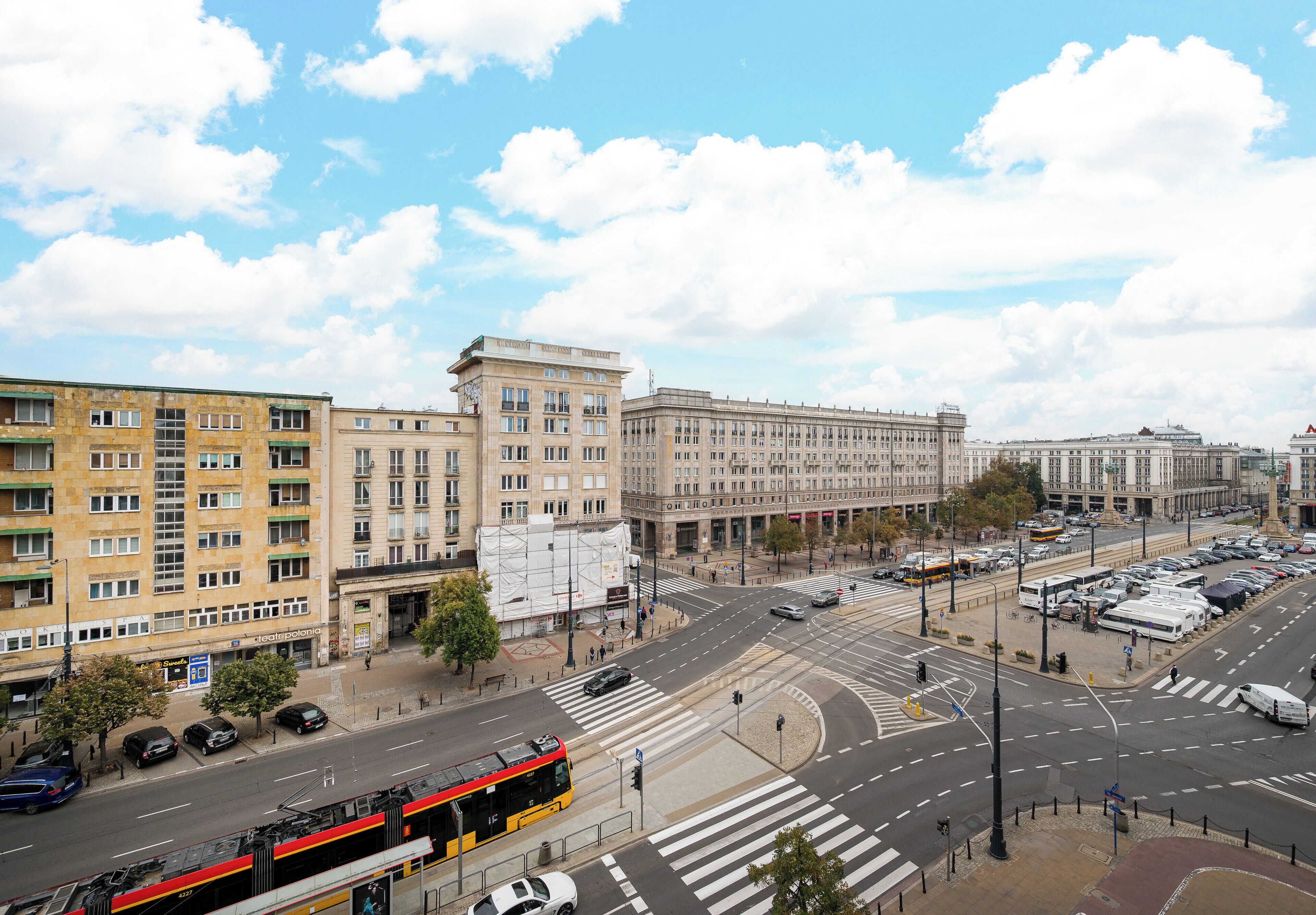 A city intersection with buildings, a bus, and cars.