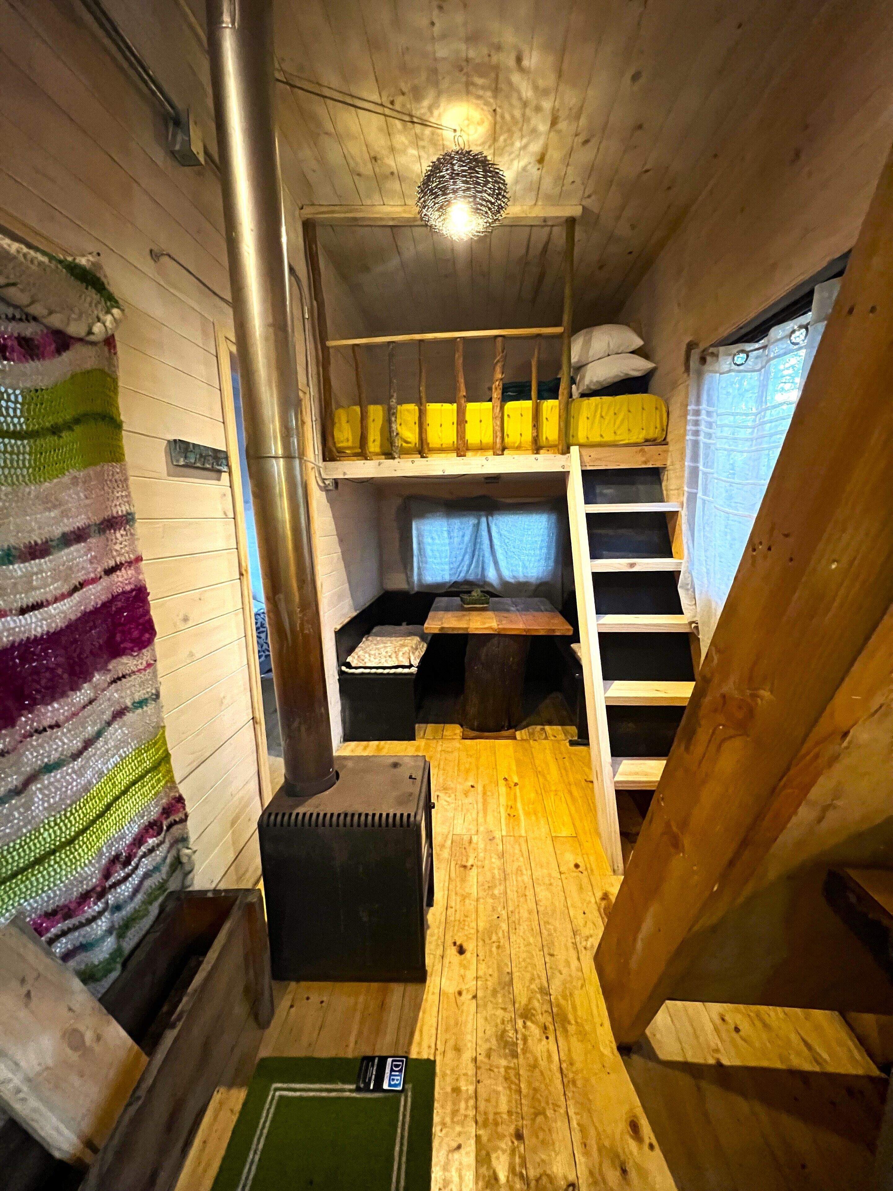 Une cabane chaleureuse avec un lit superposé, une petite table et un radiateur.