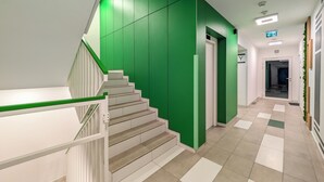 A modern staircase with green walls and white railings, leading to a door marked with a 'Y' sign. - Artemskiej Comfort Apartment (Wrocław)