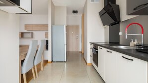 Une cuisine moderne avec des armoires blanches, un comptoir noir et un robinet rouge.