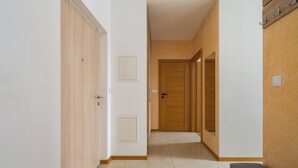 Un couloir avec des portes en bois, un banc et un porte-manteau fixé au mur.