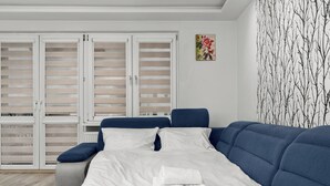 Een moderne slaapkamer met een groot bed, een blauwe bank en een garderobe met schuifdeuren.