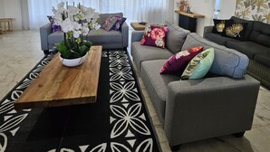 Un salon moderne avec un canapé gris, une table basse en bois et un tapis à motifs noir et blanc.
