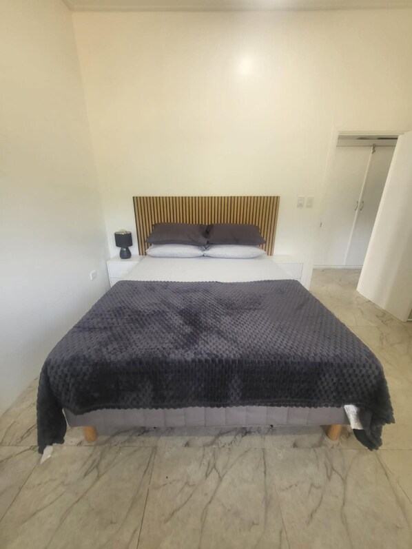 Ein Schlafzimmer mit Bett, Nachttisch, Lampe und Tür.