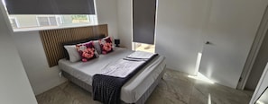 A bedroom with a bed, a headboard, a window, and a door.