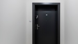 Musta ovi, jossa on numero 18, ovenkahva ja seinässä vasemmalla puolella oleva valokytkin.