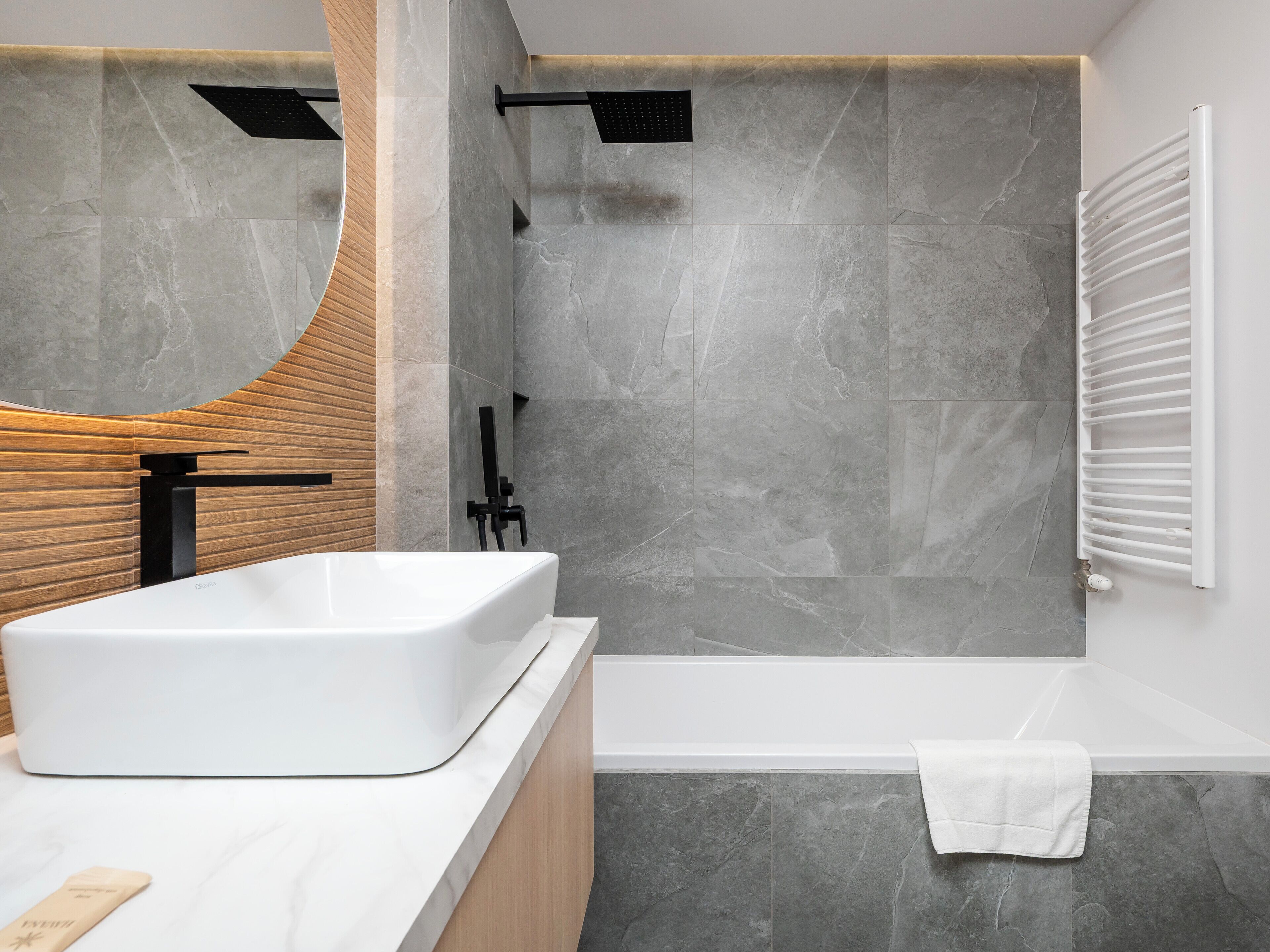 Ein modernes Badezimmer mit einer großen Badewanne, einer Dusche und einem Waschtisch mit Spiegel.