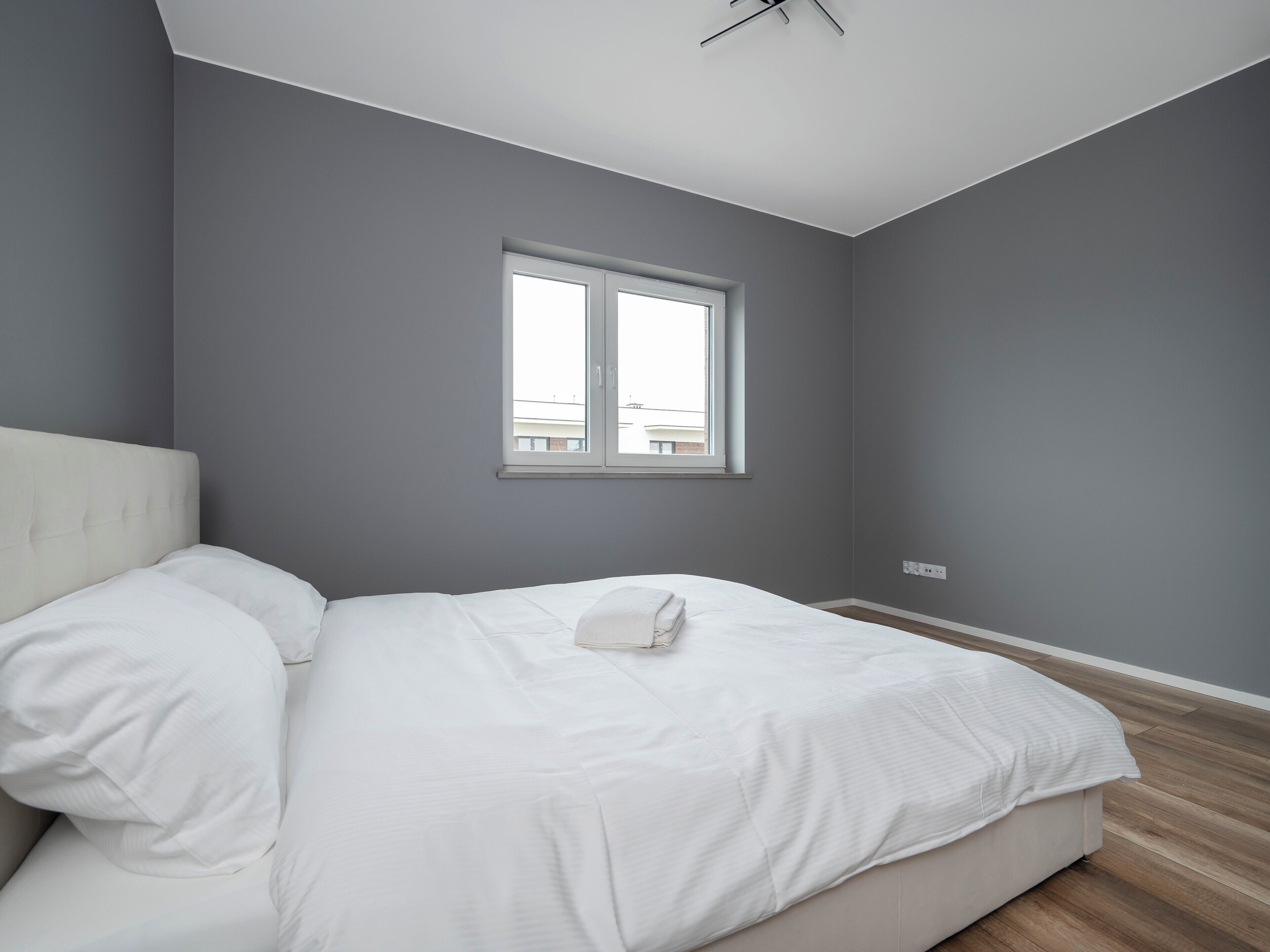 Une chambre à coucher avec un lit, une fenêtre et un interrupteur sur le mur.