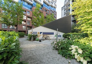 Un patio con un edificio moderno, bicicletas y abundante vegetación.