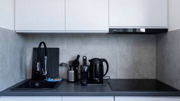 A modern kitchen with a black induction cooktop, a Bosch coffee maker, and a kettle.