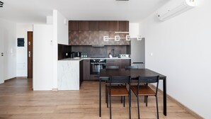 Eine moderne Küche mit Holzausstattung, einem eingebauten Backofen und einem Essbereich mit Holztisch und Stühlen.