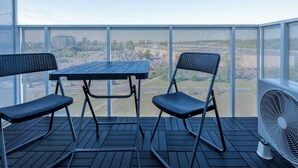 Ein Balkon mit Tisch und zwei Stühlen mit Blick auf eine Stadtlandschaft.